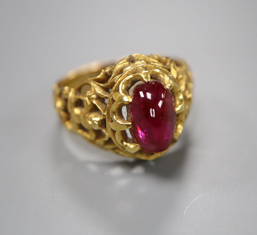 An Indian? pierced yellow metal and cabochon red stone set dress ring, size N/O, gross 8 grams.